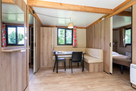 Licht, modern interieur van Mobile home Vancouver met eetruimte, ramen en een zichtbaar slaapgedeelte.