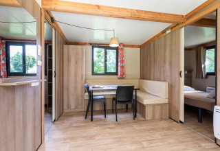 Licht, modern interieur van Mobile home Vancouver met eetruimte, ramen en een zichtbaar slaapgedeelte.