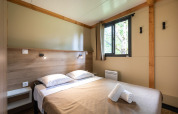Innenraum der Mobile home Vancouver Hütte mit Doppelbett, Fenster, Holzverkleidung und minimalistischer Einrichtung.