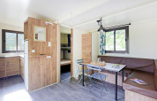 Sala luminosa y moderna en la Mobile Home Vancouver, con cocina, mesa de comedor y literas al fondo.