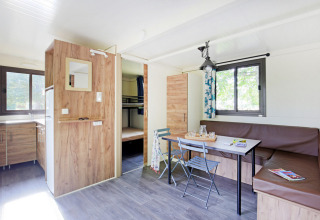 Sala luminosa y moderna en la Mobile Home Vancouver, con cocina, mesa de comedor y literas al fondo.