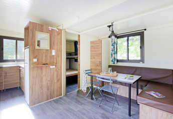 Sala luminosa y moderna en la Mobile Home Vancouver, con cocina, mesa de comedor y literas al fondo.