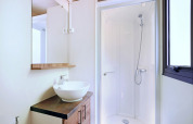 Baño moderno con cabina de ducha, espejo, lavabo y ventana en la cabaña Mobile home Vancouver.