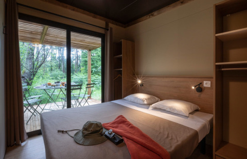 Slaapkamer van Chalet Ottawa bij Huttopia Etang de Fouché, Frankrijk, met terras en zicht op het bos.