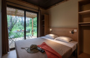 Habitación de Chalet Ottawa en Huttopia Etang de Fouché, Francia, con terraza y vistas al bosque exterior.