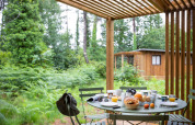 Mesa de desayuno al aire libre en Chalet Ottawa, Huttopia Etang de Fouché, Francia, rodeada de naturaleza y bosque.