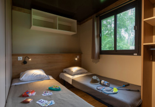 Gezellige kamer met twee aparte bedden in Chalet Ottawa, Huttopia Etang de Fouché, Frankrijk, met spelletjes.