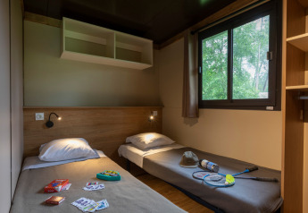 Habitación acogedora con dos camas individuales en el Chalet Ottawa de Huttopia Etang de Fouché, Francia.