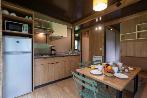 Cocina moderna y comedor en Chalet Ottawa, Huttopia Etang de Fouché, Francia, preparado para el desayuno.