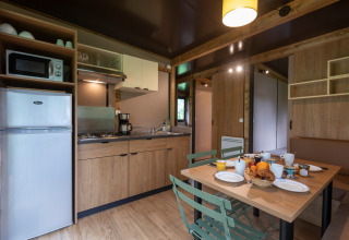 Cocina moderna y comedor en Chalet Ottawa, Huttopia Etang de Fouché, Francia, preparado para el desayuno.
