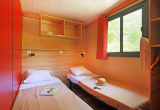 Innenansicht des Chalet Ottawa bei Huttopia Etang de Fouché in Frankreich mit zwei Einzelbetten am Fenster.