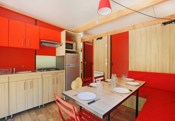 Cocina y comedor moderno en el Chalet Ottawa de Huttopia Etang de Fouché, Francia, con detalles en rojo vibrante.