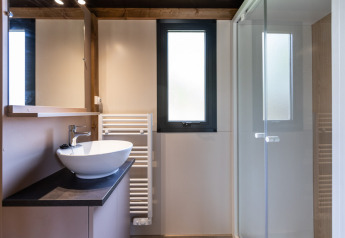 Baño moderno en Chalet Victoria, Huttopia Gorges du Verdon, Francia, con lavabo, ducha y ventana.