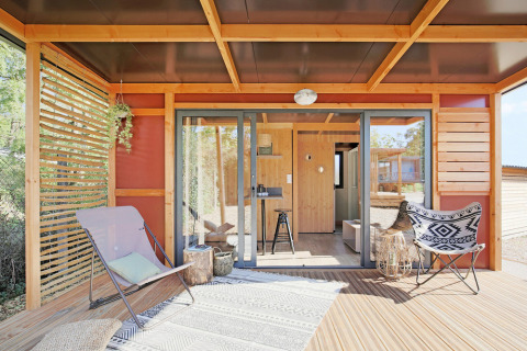 Buitenpatio van Chalet Victoria bij Huttopia Gorges du Verdon, Frankrijk, met moderne stoelen en houten details.