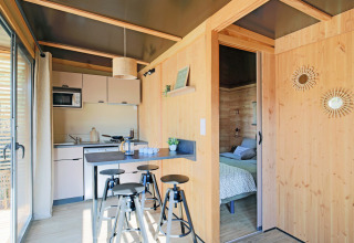 Vista interior del Chalet Victoria en Huttopia Gorges du Verdon, Francia, con paredes de madera y cocina moderna.
