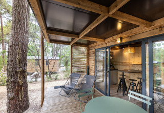 Terraza de madera en Chalet Victoria en Huttopia Gorges du Verdon, Francia, con sillas y naturaleza.