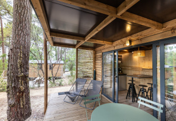 Træveranda ved Chalet Victoria på Huttopia Gorges du Verdon med afslappende stole og udsigt til naturen.