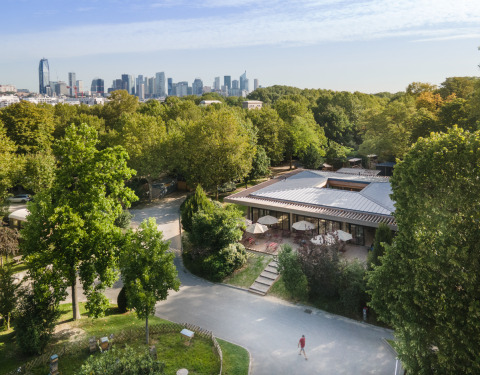 Luftfoto af Camping de Paris feriepark i Île de France, omgivet af grønt og med byens skyline i baggrunden.