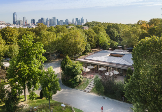 Luftfoto af Camping de Paris feriepark i Île de France, omgivet af grønt og med byens skyline i baggrunden.