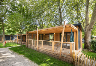 Træhytter ved Camping de Paris feriepark, omgivet af grønne træer i Île de France, Frankrig.
