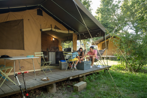 Familia disfruta en la terraza de su tienda en Camping de Paris, parque vacacional en Île de France, Francia.