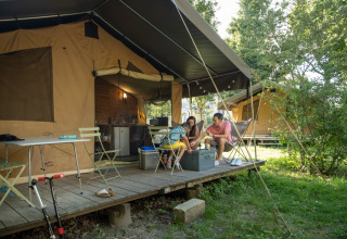 Familie nyder camping foran telt, omgivet af natur, på Camping de Paris feriepark i Île de France, Frankrig.