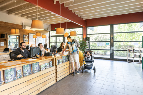 Receptionen på Camping de Paris i Île de France med gæster og personale, sollys gennem store vinduer.