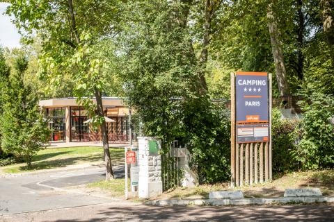 Entrada del Camping de Paris en Île de France, Francia, un parque de vacaciones rodeado de naturaleza y árboles.