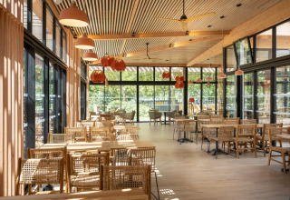 Helles Restaurant mit Holzmöbeln und großen Fenstern im Camping de Paris, Île de France, Frankreich.