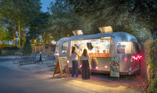 Vue nocturne d’un food truck au Camping de Paris, Île de France, France, servant des clients dehors.