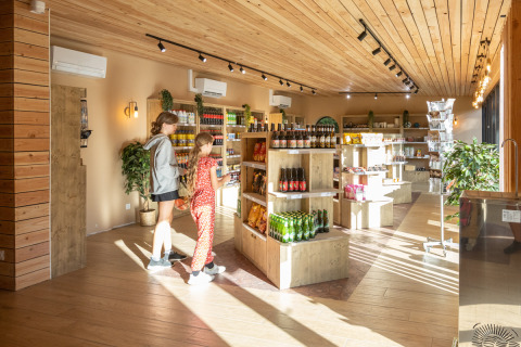 Escena de compras en la tienda de Camping de Paris, con dos personas y estantes iluminados.