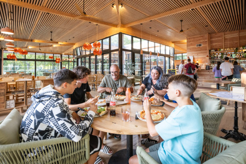 Gezin eet samen pizza in een modern restaurant op Camping de Paris, Île de France, Frankrijk.
