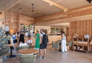 Folk nyder en moderne café i træ på Camping de Paris, Île de France, Frankrig med afslappet atmosfære.