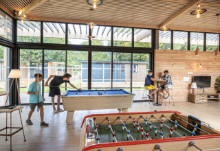 Des enfants jouent au billard et au baby-foot dans une salle lumineuse au Camping de Paris, Île de France.