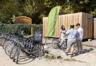 Billede af gæster, der lejer elektriske cykler ved Camping de Paris i naturskønne omgivelser.