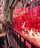 Personas observan un escaparate navideño iluminado de rojo en una calle cerca de París, Île-de-France, Francia.