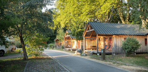 Cabañas de madera y árboles verdes junto a un sendero en Camping de Strasbourg, parque vacacional en Grand Est, Francia.
