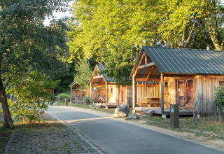 Houten chalets en groene bomen langs een wandelpad bij Camping de Strasbourg, vakantiepark in Grand Est, Frankrijk.
