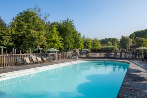 Outdoor swimming pool with sun loungers and wooden deck surrounded by trees at Camping de Strasbourg, France.