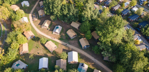 Vue aérienne de tentes et cabanes entre les arbres au Camping de Strasbourg, parc de vacances, Grand Est, France.