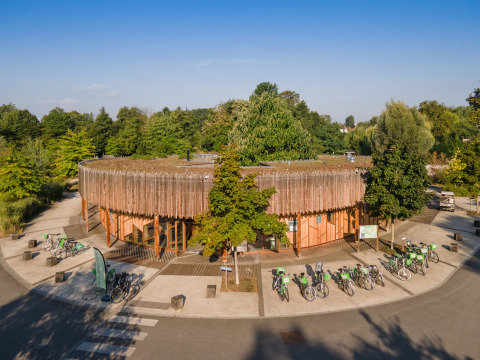 Edificio redondo de madera y bicicletas rodeados de árboles en Camping de Strasbourg, Grand Est, Francia.