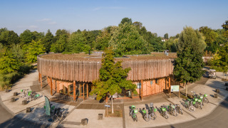 Edificio redondo de madera y bicicletas rodeados de árboles en Camping de Strasbourg, Grand Est, Francia.