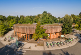 Edificio redondo de madera y bicicletas rodeados de árboles en Camping de Strasbourg, Grand Est, Francia.