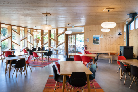 Sala da pranzo luminosa e moderna con mobili in legno e sedie colorate al Camping de Strasbourg, Francia.
