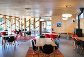 Lichte en moderne eetzaal met houten tafels en kleurrijke stoelen in Camping de Strasbourg, Frankrijk.