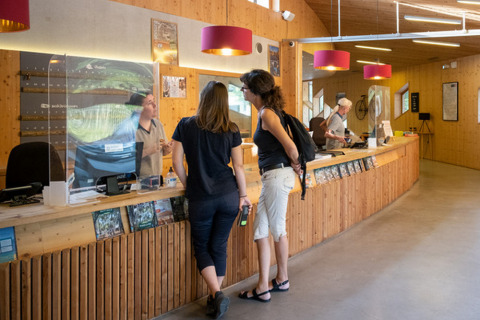 Huéspedes conversan con el personal en la recepción de Camping de Strasbourg, un parque vacacional en Grand Est, Francia.