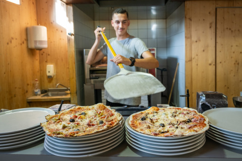 En pizzabager tilbereder pizzaer i et køkken på Camping de Strasbourg, Grand Est, Frankrig.