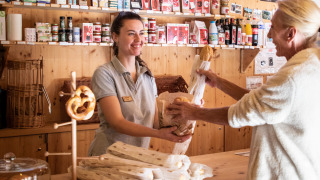 Una dependienta sonriente entrega pan fresco a una clienta en la tienda de Camping de Strasbourg, Francia.