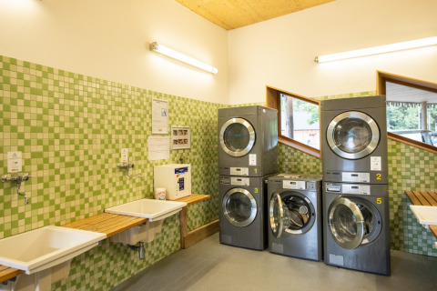 Lavandería en Camping de Strasbourg con lavadoras modernas, azulejos verdes y lavabos junto a la pared.