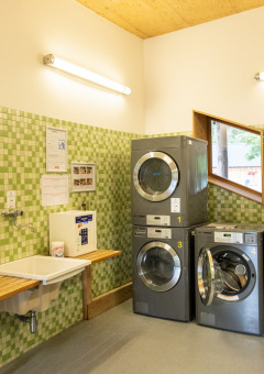 Lavandería en Camping de Strasbourg con lavadoras modernas, azulejos verdes y lavabos junto a la pared.
